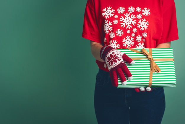 Mädchen in Kleidern mit einer Weihnachtsverzierung hält eine Geschenkbox