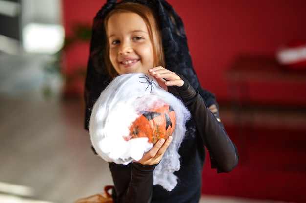 Mädchen in Maske zu Hause im Halloween-Kostüm mit Kürbis Jack oder Laurent