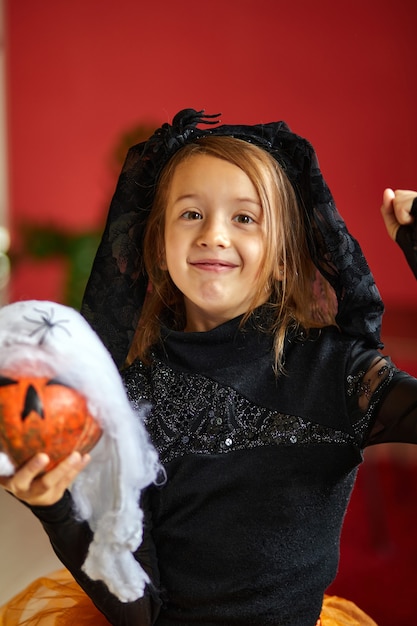 Foto mädchen in maske zu hause im halloween-kostüm mit kürbis jack oder laurent