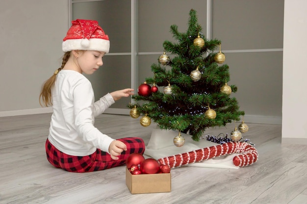 Mädchen in Nikolausmütze schmückt den Weihnachtsbaum Weihnachtsinhalt