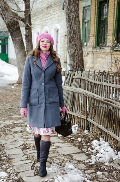 Mädchen in rosa Baskenmütze und graublauem Mantel geht die Straße der Altstadt entlang