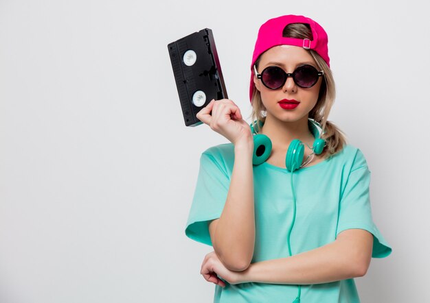 Mädchen in rosa Mütze und blauem T-Shirt mit VHS-Kassette