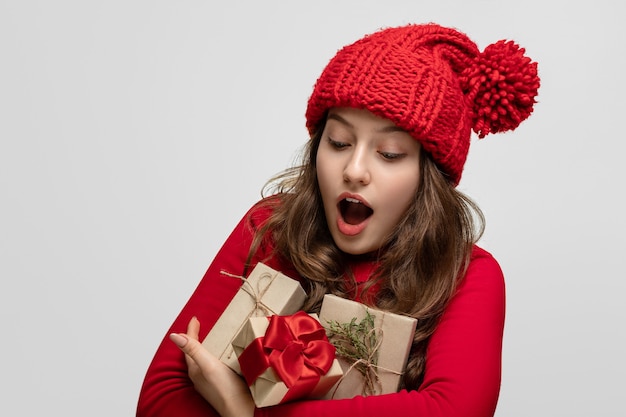 Mädchen in Rot mit einem Armvoll Geschenken, Freude im Gesicht. Der Blick ist auf die Geschenke gerichtet