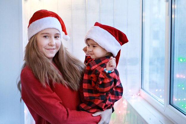 Mädchen in roten Weihnachtsmützen. Schwestern in Weihnachtskostümen.