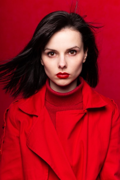 Mädchen in roter Kleidung mit rotem Lippenstift auf den Lippen roter Hintergrund