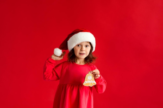 Mädchen in Sankt-Hut mit Weihnachtslebkuchenglocke