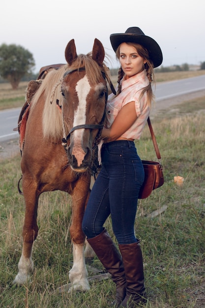 Mädchen in schwarzen Huthemdjeans des Cowboys mit Pferd