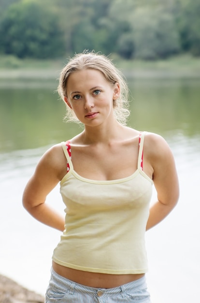 Mädchen in Shorts und Top posiert am Ufer des Sees