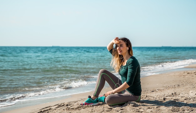 Mädchen in Sportbekleidung Fitness am Meer zuhören