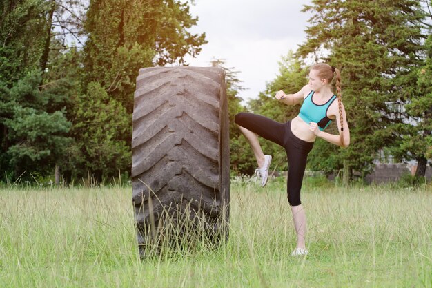 Foto mädchen in sportkleidung schlägt einen reifen mit dem knie