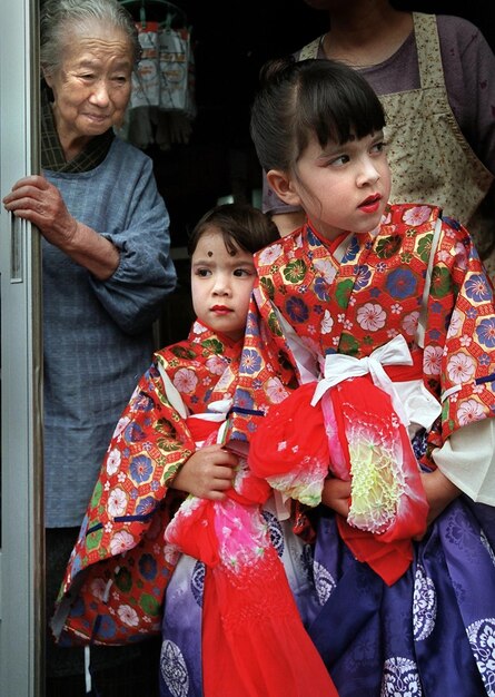 Mädchen in traditioneller Kleidung stehen mit Mutter und Großmutter