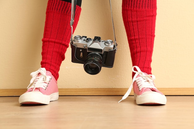 Mädchen in Turnschuhen mit Retro-Fotokamera im Zimmer