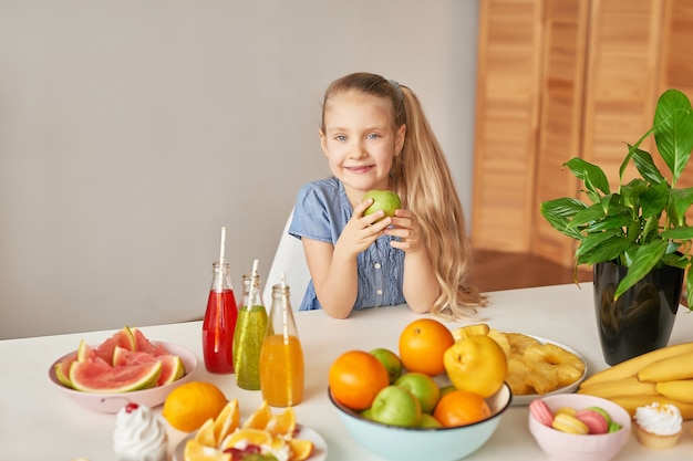 Mädchen isst Obst auf einem Tisch voller Essen