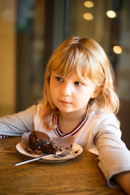 Mädchen isst Schokoladenkuchen zum Nachtisch in einem Café