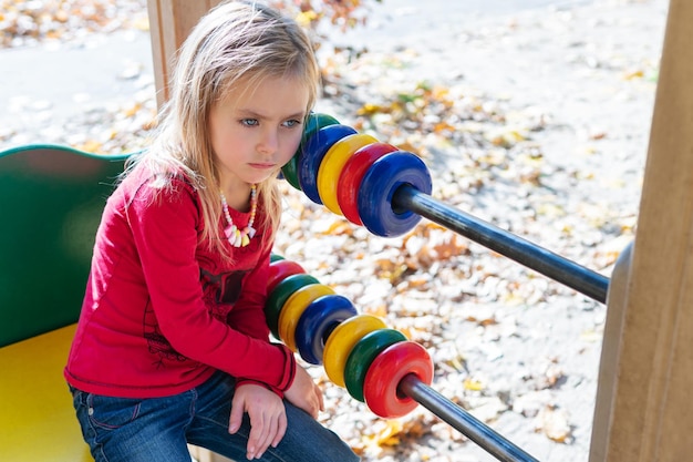 Mädchen ist müde vom Zählen, während sie auf dem Spielplatz sitzt