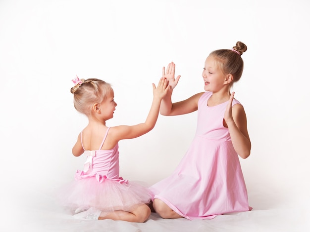 Mädchen junge Ballerinas in rosa Kleidern auf hellem Hintergrund