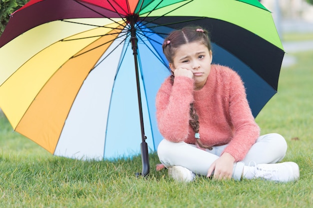 Mädchen Kind einsam traurig Gesicht sitzen Park unter Regenschirm Bleiben Sie positiv und optimistisch Buntes Zubehör positiver Einfluss Heller Regenschirm Finden Sie friedlichen privaten Raum zum Entspannen unter einem großen Regenschirm