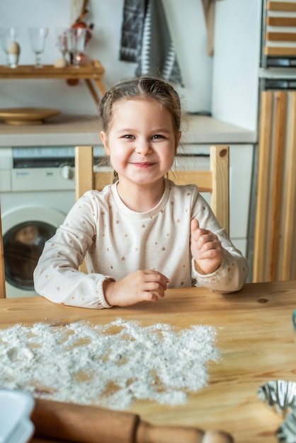 Mädchen kocht zu Hause in einer hellen Küche ein Kind rührt Mehl auf dem Tisch Baby hilft Mama und lacht