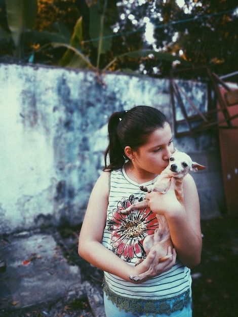 Mädchen küsst Chihuahua-Hund im Hinterhof