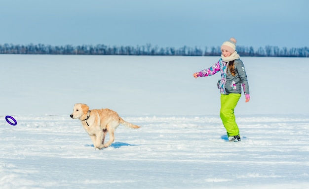 Mädchen läuft mit Hund im Schnee