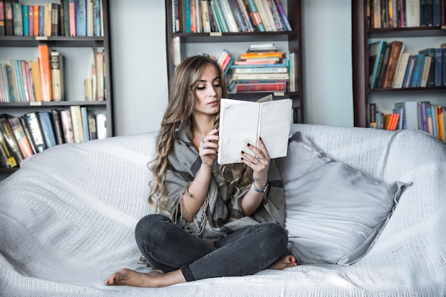 Mädchen liest Buch auf Sofa