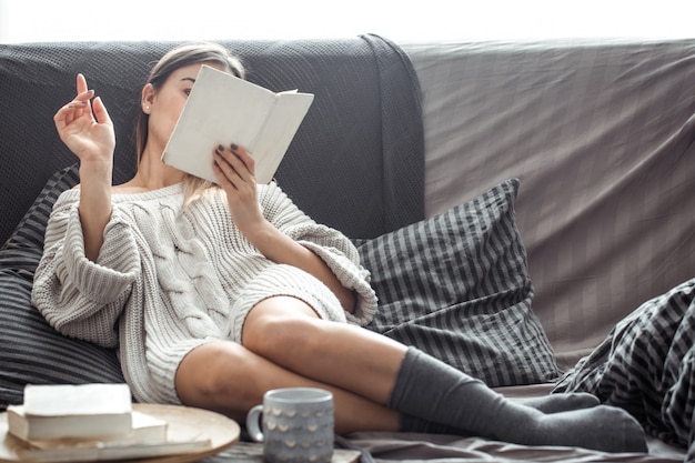 Mädchen liest Buch auf Sofa