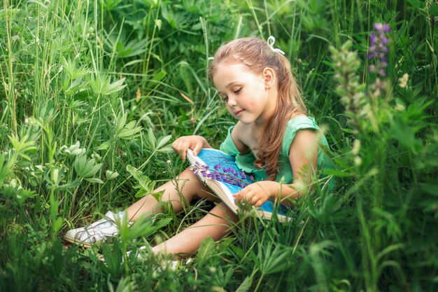 Mädchen liest im Sommer ein Buch in der Natur