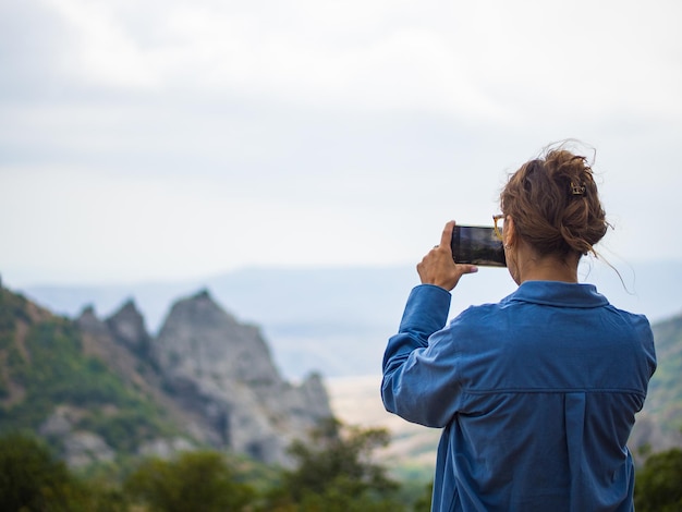 Mädchen macht auf ihrem Handy Bilder von Berglandschaften