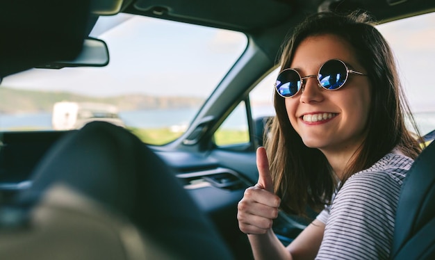 Mädchen macht Daumen hoch im Auto