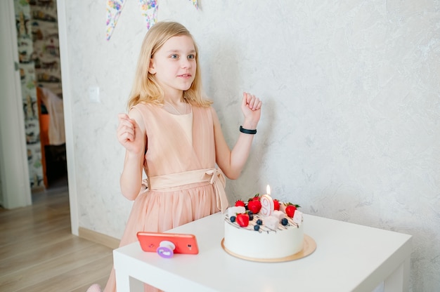 Mädchen macht einen Wunsch, es gibt einen Kuchen auf dem Tisch