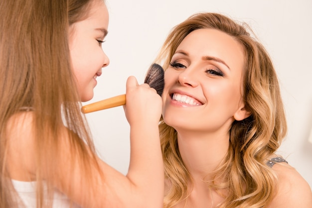 Mädchen macht Make-up zu ihrer fröhlichen Mutter