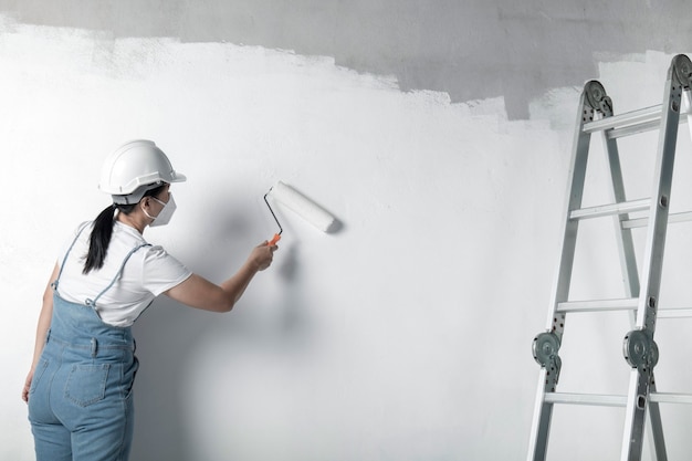 Mädchen malt eine weiße Wand mit einer Rolle. Reparatur des Innenraums.