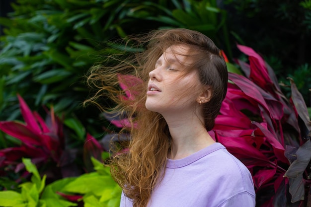 Mädchen meditiert in einem Park in der Natur oder betet in einem tropischen Garten, entspannt sich in der Natur und atmet