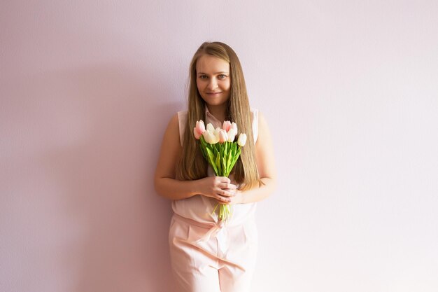 mädchen mit blonden aufgelösten langen haaren hält ein filzhut auf dem kopf frühlingsblumen in ihren händen