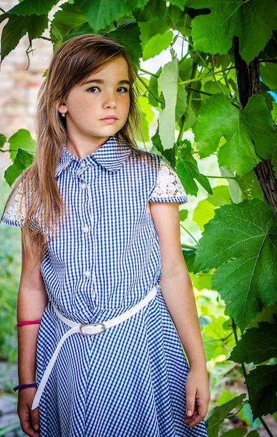 Mädchen mit blonden Haaren in einem blauen Kleid in einem Obstgarten im Sommer