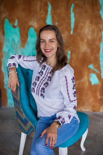 Mädchen mit braunen Haaren sitzt auf blauem Stuhl