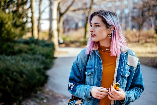 Mädchen mit dem bunten Haar, das auf jemand am Park wartet.