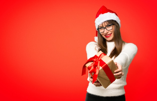 Mädchen mit dem Feiern der Weihnachtsfeiertage, die Geschenkboxen in den Händen auf rotem Hintergrund halten