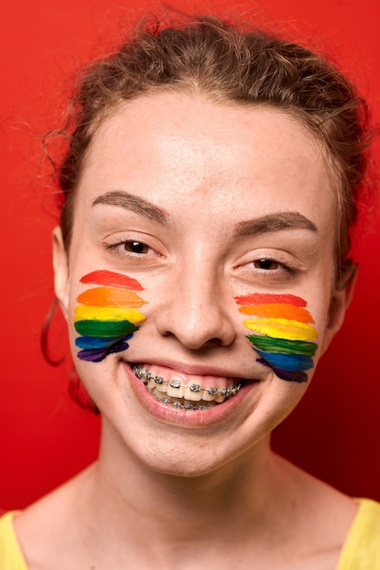 Foto mädchen mit der stolzflagge gemalt auf ihrem backenlächeln