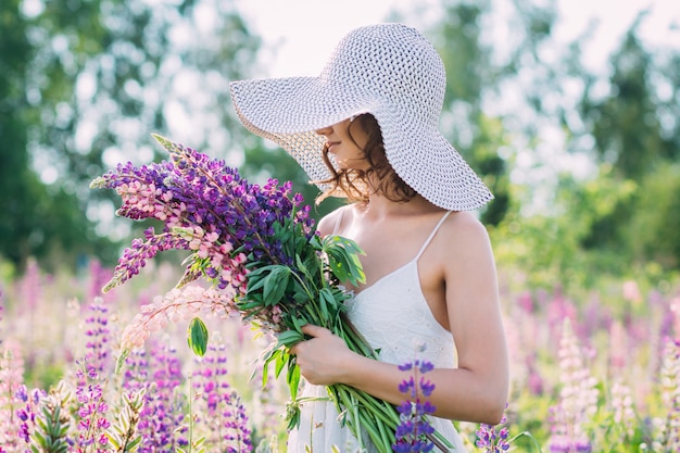 Mädchen mit einem Blumenstrauß von Lupine auf dem Feld