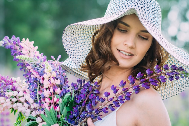 Mädchen mit einem Blumenstrauß von Lupine auf dem Feld