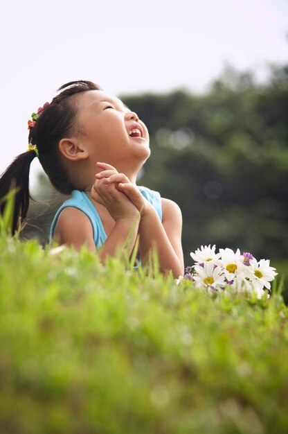 Mädchen mit einem Bündel Blumen, das auf einem grasbewachsenen Feld im Park liegt