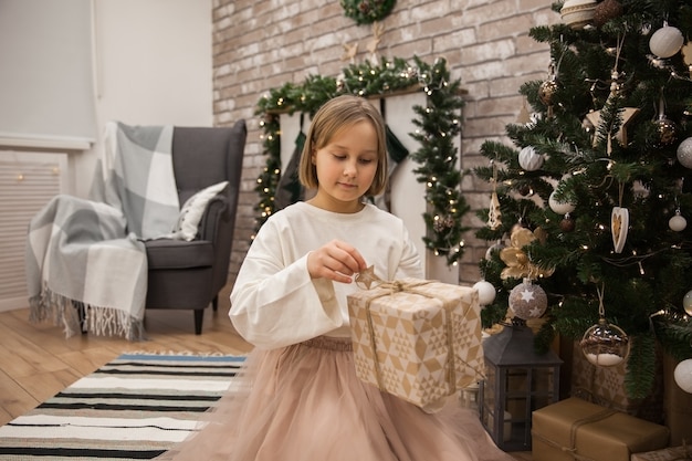 Mädchen mit einem Geschenk am Weihnachtsbaum