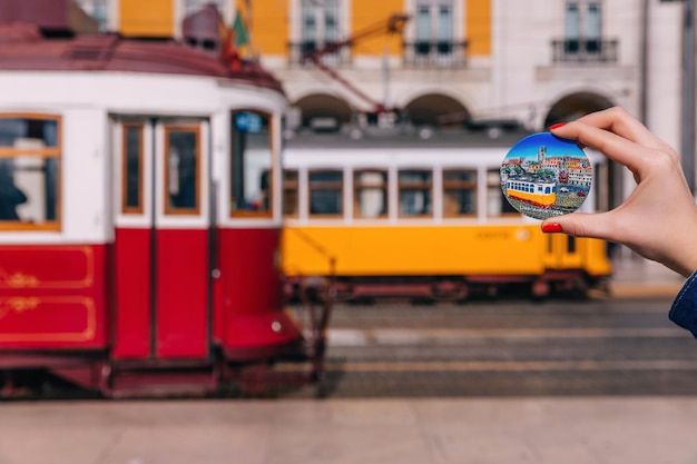 Foto mädchen mit einem keramikgeschenk mit dem bild der berühmten gelben straßenbahn in lissabon rote und gelbe straßenbahnen auf den straßen von lissabon