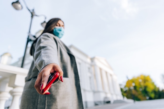 Mädchen mit einem roten Handy in der Hand in einem Stadtbild