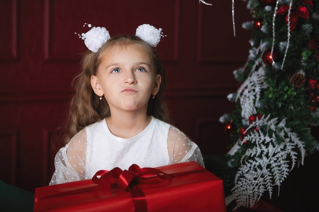 Mädchen mit einem roten Kasten in der Hand. Weihnachtsgeschenk, frohes neues Jahr.