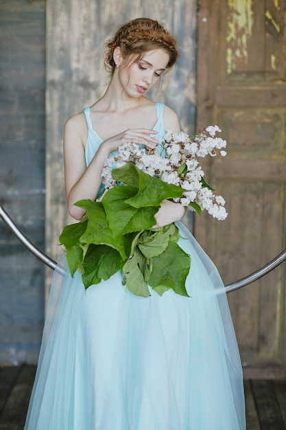 Mädchen mit einem schönen Blumenstrauß in einem blauen Kleid