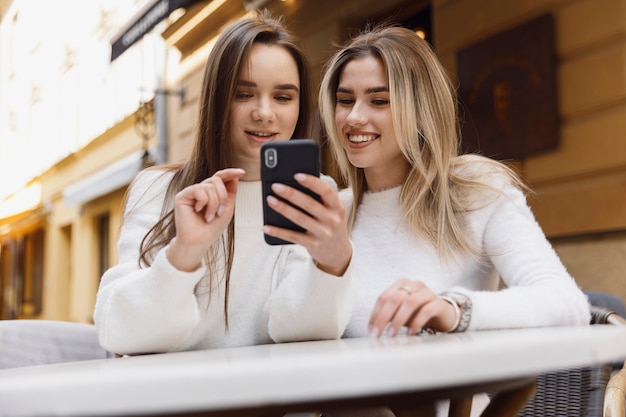 Mädchen mit einem Smartphone an einem Cafeteriatisch