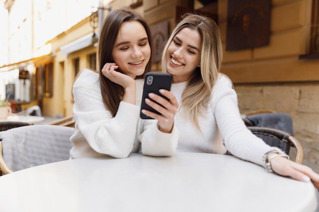 Mädchen mit einem Smartphone an einem Cafeteriatisch