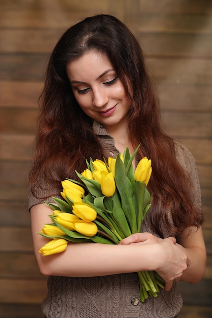Mädchen mit einem Strauß gelber Tulpen Mädchen mit einem Blumengeschenk in einer Vase Ein Geschenk für Mädchen an einem weiblichen Feiertag mit gelben Tulpen auf floorxA